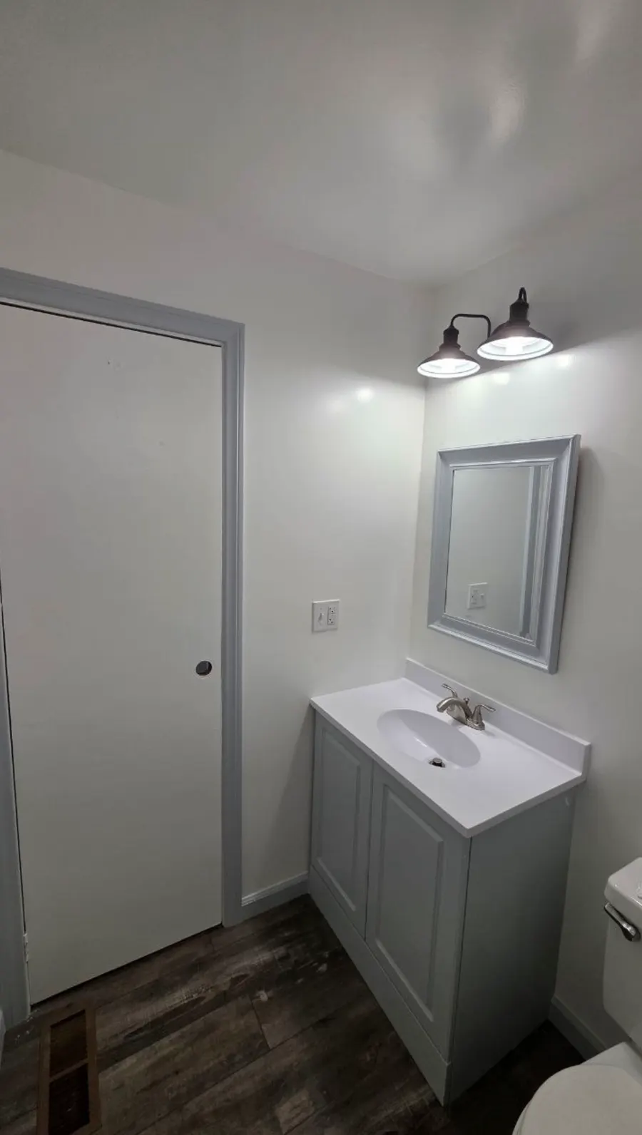 After: the same bathroom with smooth white walls, new vanity and mirror