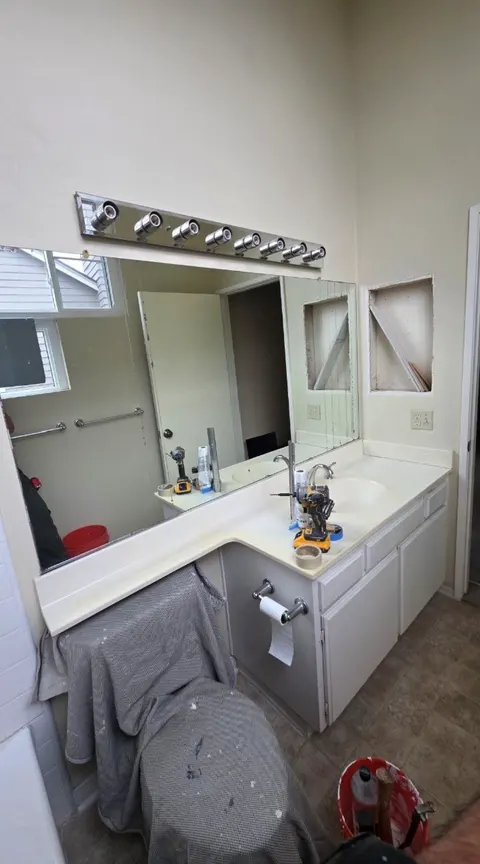 Before: old vanity with two open holes in the wall beside the mirror